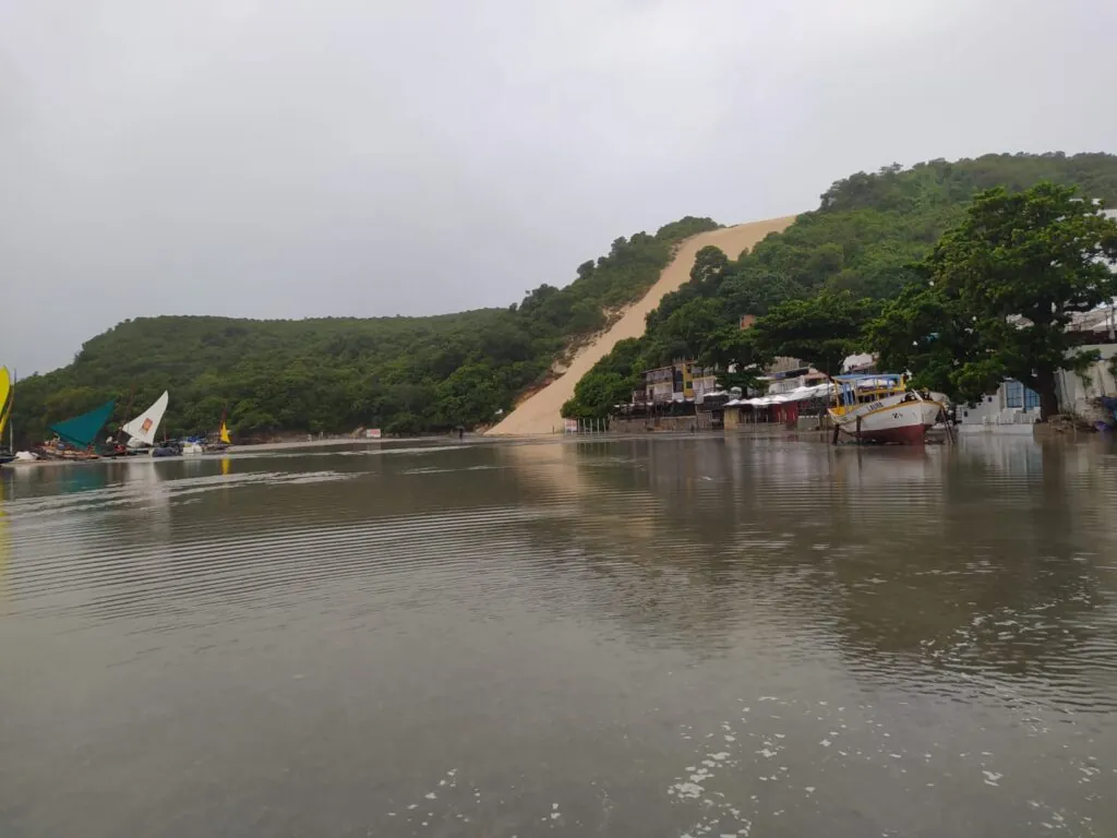 Faixa de areia é arrastada pela água em Ponta Negra; chuva derruba cerca de proteção do Morro do Careca